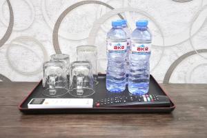 ein Tablett mit Wasserflaschen und Gläsern sowie einer Fernbedienung in der Unterkunft Amor fati hotel Tashkent in Yakkasaray