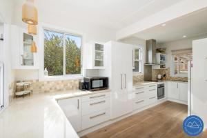 une cuisine blanche avec des armoires blanches et un micro-ondes dans l'établissement Shoal Bay Beach House & Garden Suite - 200m to iconic beach, à Shoal Bay 15 autres photos