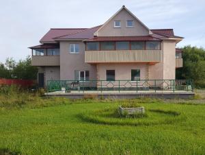 a large house with a grass field in front of it at Guest House Kim House in Yuzhno-Sakhalinsk