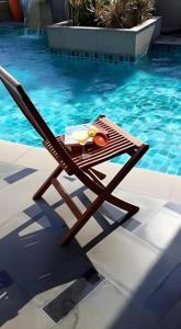 einem Holzstuhl neben einem Pool in der Unterkunft The Sez Hotel Bangsaen in Ban Laem Thaen