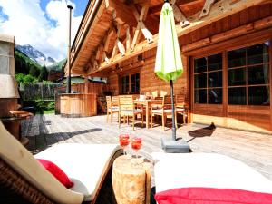 une cabane en bois avec une table, des chaises et un parasol dans l'établissement Luxury Chalets Wiesenruh, à Bichlbach
