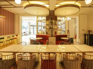 ein Restaurant mit Tischen und Stühlen in einem Raum in der Unterkunft Magnotel Business Jining Huancheng North Road in Jining