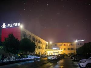 ein Gebäude mit nachts auf einem Parkplatz geparkt in der Unterkunft Magnotel Business Jining Huancheng North Road in Jining