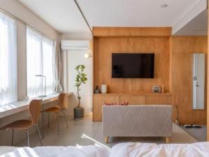 ein Wohnzimmer mit einem Sofa und einem Fernseher an der Wand in der Unterkunft Nest West Garden Tosa Hotel in Kuroshio