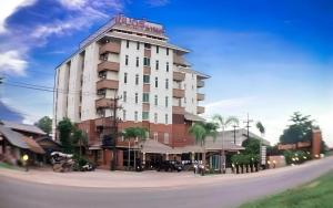 a large building with palm trees in front of a street at Century Grand Hotel in Bung Kan