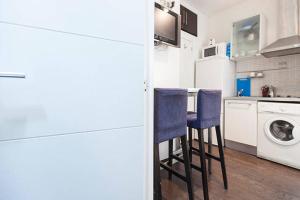 cocina con lavadora y 2 taburetes azules en Piramides 2 Apartment en Madrid