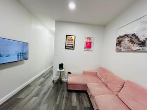 a living room with a pink couch and paintings at VibeHaus Midtown in New York