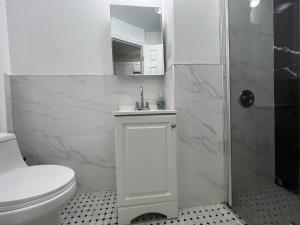 a white bathroom with a toilet and a shower at VibeHaus Midtown in New York