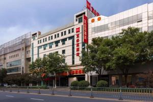 a large white building with a red sign on it at Ibis Xinzhou Qiyi RD in Xinzhou Zhan