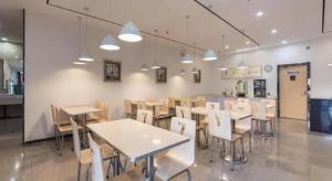 un restaurant avec des tables et des chaises dans une salle dans l'établissement 7 Days Premium Jinan Gaoxin Qu Wanda Plaza, à Jinan