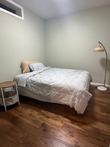 a bedroom with a bed and a lamp on a wooden floor at Spacious Basement with independent entry and yard in Issaquah +2 photos