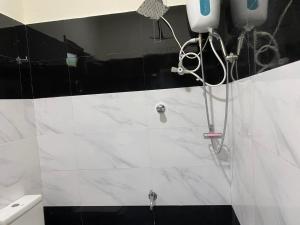 a shower in a bathroom with white and black tiles at Naren Guest House in Kallady