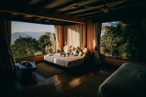 une chambre avec un lit et une grande fenêtre dans l'établissement Dwarika's Sanctuary, à Dhulikhel 53 autres photos