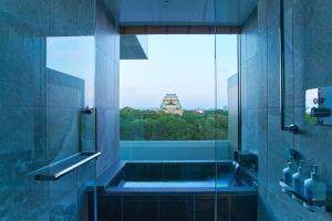a bathroom with a shower with a view of a pagoda at Espacio Nagoya Castle, The Leading Hotels of the World "LHW" in Nagoya