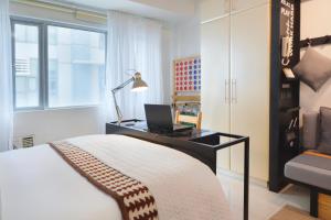 1 dormitorio con escritorio y ordenador portátil. en Relaxing Apt Bgc Business Ready with 84inch Cinema, en Manila 21 fotos más