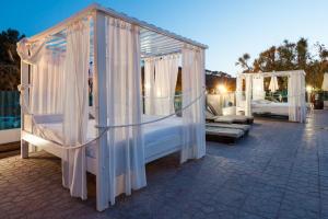 a group of four beds with white curtains at Aparthotel Puerto Cala Vadella in Cala Vadella +127 photos