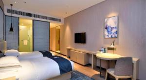 ein Schlafzimmer mit einem Bett, einem Schreibtisch und einem Fernseher in der Unterkunft Echarm Hotel Xian Ming City Wall South Gate in Xi'an