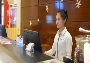 a woman sitting at a table with a laptop computer at City Comfort Inn Zhanjiang Mazhang Pedestrian Street High-speed Railway West Station in Tchia-k'am