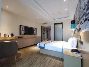 a hotel room with a bed and a television at City Comfort Inn Wanning Wan'An Avenue High Speed Railway Station in Wanning