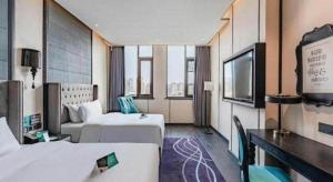 a hotel room with two beds and a television at Xana Hotelle Luzhou High-Speed Railway Station Trading Market Passenger Terminal in Luzhou