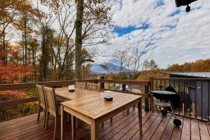 una terraza de madera con mesa y sillas de madera en 富士山を見ながらサウナBBQ The No10 MtFuji Forest House, en Yamanakako