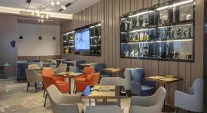 ein Restaurant mit Tischen und Stühlen und einem Fernseher in der Unterkunft Echarm Hotel Wuhan High-speed Rail Peace Park Metro Station in Wuhan