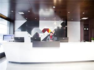 a man sitting at a counter in an office at Borrman Hotel Huanggang Wuxue Yuhu Road in Wuxue