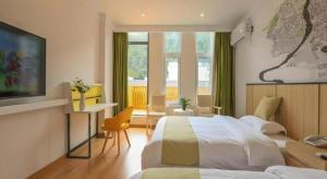 um quarto de hotel com duas camas e uma televisão em Vatica Hotel Huangshan South Gate Terminal Station em Área Cénica das Montanhas Huangshan