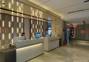 two men sitting at a reception desk in a lobby at Echarm Hotel Nanchang Bayi Square Metro Station Wushang MALL in Nanchang