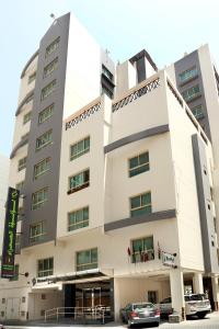 a building with cars parked in front of it at Desert Pearl Hotel Apartment in Manama