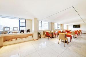 ein Esszimmer mit Tischen und Stühlen und Fenstern in der Unterkunft City Comfort Inn Kunshan High-speed Railway Station Renmin Road in Kunshan