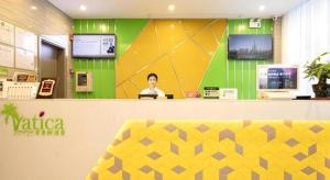 a woman sitting at a counter in a store at Vatica Hotel Haikou Jinniuling Park Haizhiyuan in Haikou