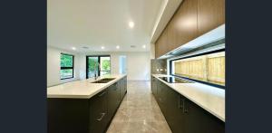 eine große Küche mit weißen Arbeitsplatten und Fenstern in der Unterkunft Sunnybank Station 5B Family Stay in Brisbane