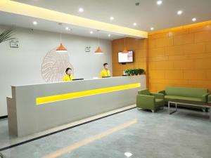 two people standing at a counter in a waiting room at Shell Hotel Liaocheng Dongchang Xi Road Railway Station in Liaocheng