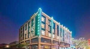 un gran edificio verde con luces en la parte superior en GreenTree Inn Express Zhangjiagang Hexing Town Shazhou Professional Institue of Technology, en Qiwei