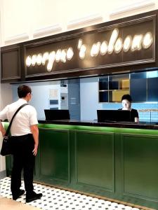 un homme debout devant un comptoir de nourriture dans l'établissement Premier City Comfort Hotel Wuhan Yellow Crane Shouyi Road Metro Station, à Wuhan