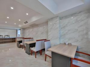 ein Esszimmer mit Tischen und weißen Stühlen in der Unterkunft Green Tree Inn Express Zhejiang Zhoushan Xincheng Zheda in Zhoushan