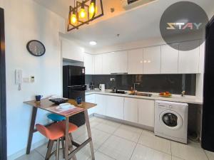 eine Küche mit weißen Schränken, einem Tisch und einer Waschmaschine in der Unterkunft Almas Suites Couple Cozy Seaview Netflix By STAY in Nusajaya