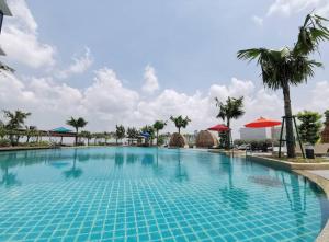 einen großen blauen Pool mit Palmen und Sonnenschirmen in der Unterkunft Almas Suites Couple Cozy Seaview Netflix By STAY in Nusajaya