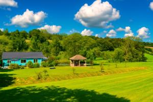 a house in a field with a gazebo at Chalet de 95m2 au cœur du Pays d'Auge, en Normandie avec Piscine et Jacuzzi in Les Champeaux