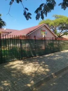 a fence in front of a pink building at Savannah Guest House Mafikeng in Mahikeng +22 photos