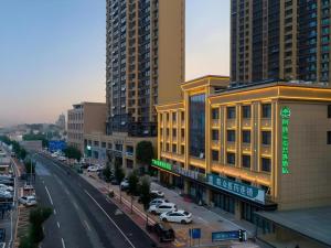 eine Stadt mit hohen Gebäuden und einer Straße mit Autos in der Unterkunft Green Tree Inn Express Heze University Town in Zhaolou
