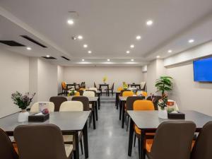 ein Esszimmer mit Tischen und Stühlen und einem Flachbildfernseher in der Unterkunft Green Tree Inn Express Heze University Town in Zhaolou
