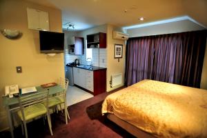 una camera con letto e tavolo e una cucina di Athena Motel a Christchurch