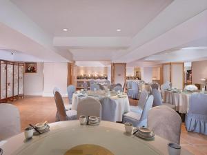 ein Restaurant mit weißen Tischen und Stühlen in einem Raum in der Unterkunft Vienna Hotel Hunan Jishou Fenghuang Ancient City in Fenghuang