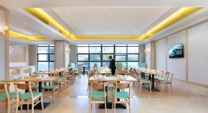 a person standing in a dining room with tables and chairs at Vienna Hotel Jiangxi Fengcheng Fnegkuang in Fengcheng