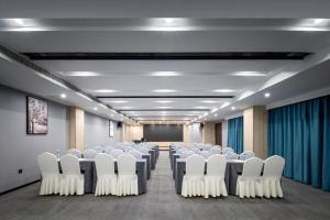 Cette chambre comprend des rangées de tables et de chaises blanches. dans l'établissement VX Hotel Wuhan Optics Valley Yangjia Bay Metro Station, à Wuhan