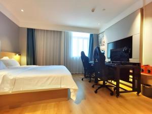 une chambre d'hôtel avec un lit, un bureau et un ordinateur dans l'établissement VX Hotel Wuhan Optics Valley Yangjia Bay Metro Station, à Wuhan