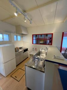 a kitchen with white appliances and a counter top at 一棟貸し宿ゲストハウスサンク in Masuda