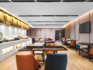 ein Esszimmer mit Tischen und Stühlen und einem Fernseher in der Unterkunft Echarm Hotel Nanjing Expo Center Olympic East Metro Station in Nanjing